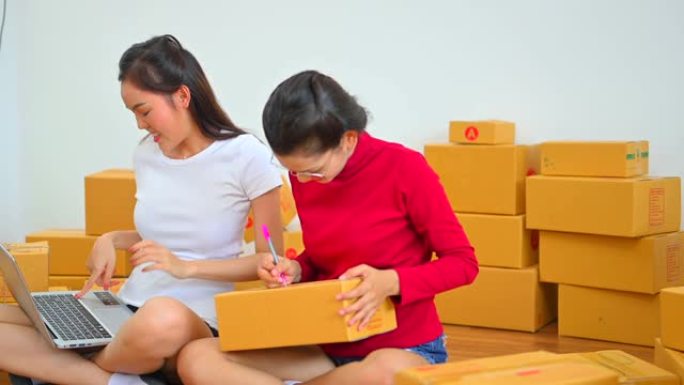 年轻的亚洲快乐女性朋友在家里的客厅一起工作，中小企业和送货电子商务概念。创业小企业企业家