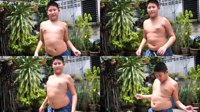 肥胖的青春期男孩在户外后院移动和摇晃他的肚子，慢动作。