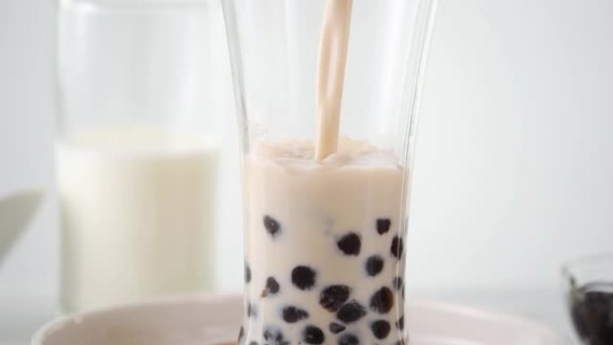将奶茶倒入带有美味的台湾木薯珍珠泡泡的水杯中。