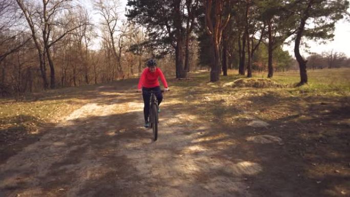 主题运动员的健康问题。骑山地自行车的白人女子自行车手在森林里完成锻炼。情绪疲惫，用力快速心跳，呼吸困