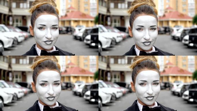 一个穿着黑色礼服外套的哑剧女孩在镜头前摆姿势。