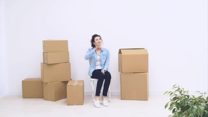 坚强的女人坐在大箱子附近，装满物品，孤立在白色背景上。4K。