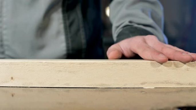 一位男木匠的手的特写检查木板的光滑度和适用性