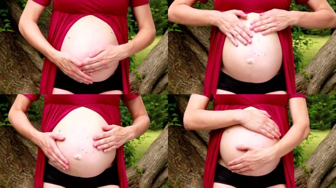 心形怀孕。未来的妈妈和父母拥抱，拥抱和抚摸腹部的手，她正在怀孕的肚子上做心脏象征。等待婴儿。怀孕，肚