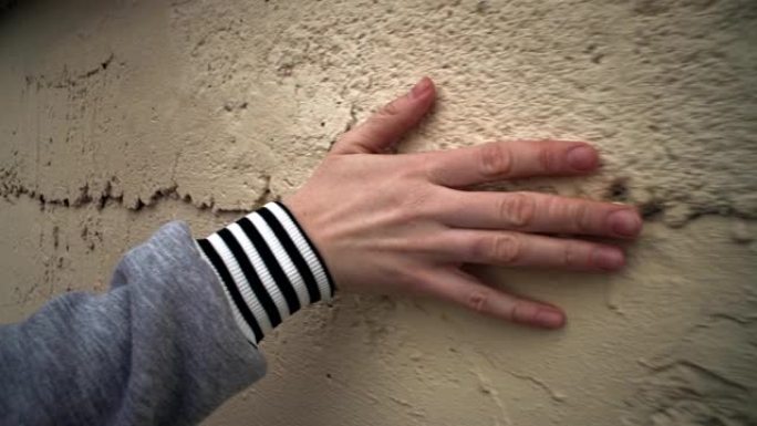 女性手触摸抹灰墙。