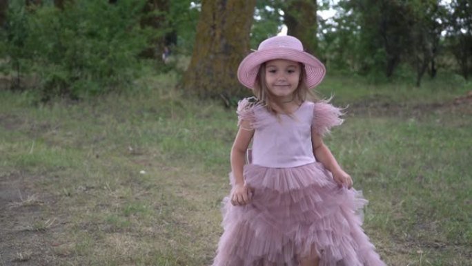 穿着漂亮的粉红色连衣裙的小女孩在大自然中行走，慢动作