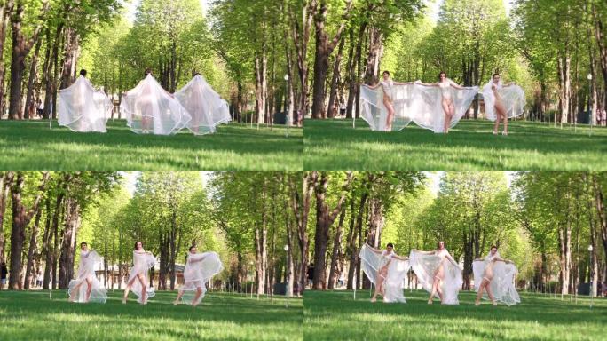 穿着性感服装和新娘面纱的女舞者在绿色公园跳舞