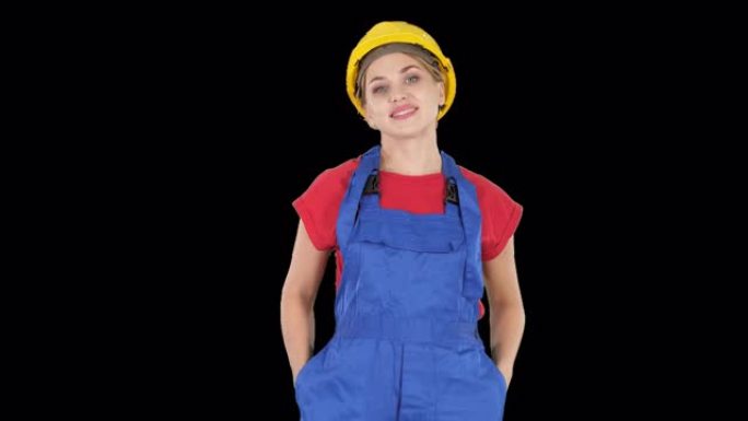 微笑的建筑工人妇女站立和改变姿势折叠手，手放在臀部，手放在口袋里，阿尔法通道