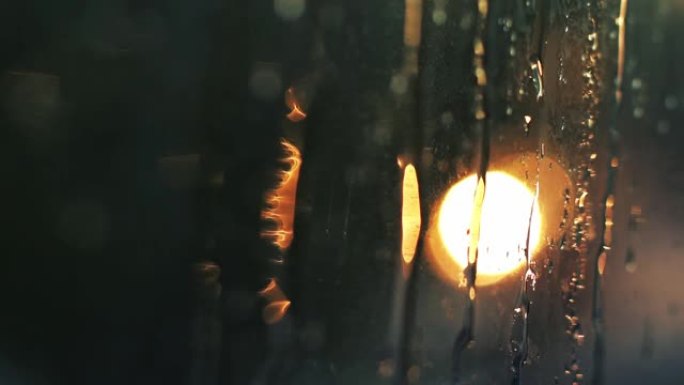 散焦夜城背景，汽车交通灯。日落日模糊的画面。小春雨在窗户上留下水珠。汽车在路上行驶并站立。文本的位置