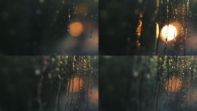 散焦夜城背景，汽车交通灯。日落日模糊的画面。小春雨在窗户上留下水珠。汽车在路上行驶并站立。文本的位置