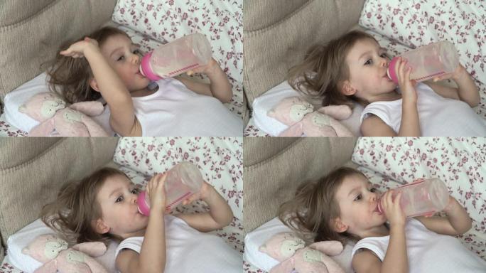 可爱的小女孩躺在床上，早上醒来的玩具粉色猫，食欲大增，抚摸头发。