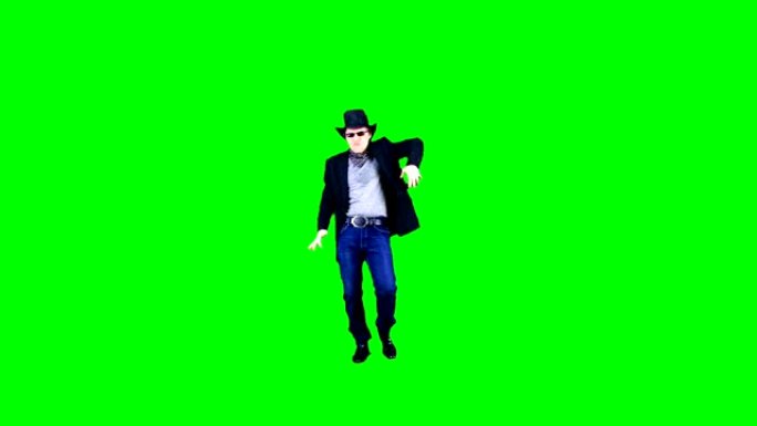 戴着帽子和太阳镜的开朗酷牛仔在色键上开玩笑地跳舞。演员在绿色背景上表演。