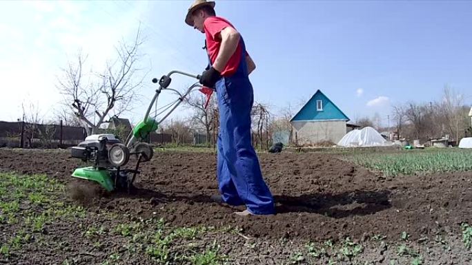 人类用耕作机在花园里耕种土地，为播种准备土壤