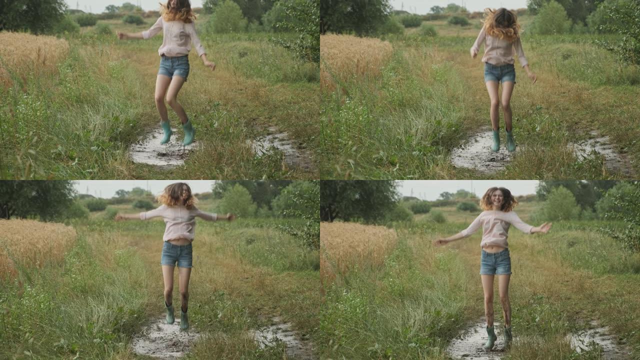 美丽微笑的少女跳进乡村道路上非常泥泞的水坑，雨后的夏天自然背景