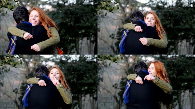 顽皮的女人在公园拥抱男友，并与相机调情