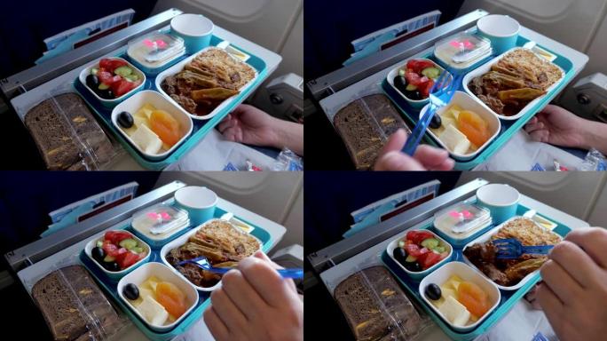 女人在飞行过程中在飞机上吃饭，食物放在托盘上，手特写。