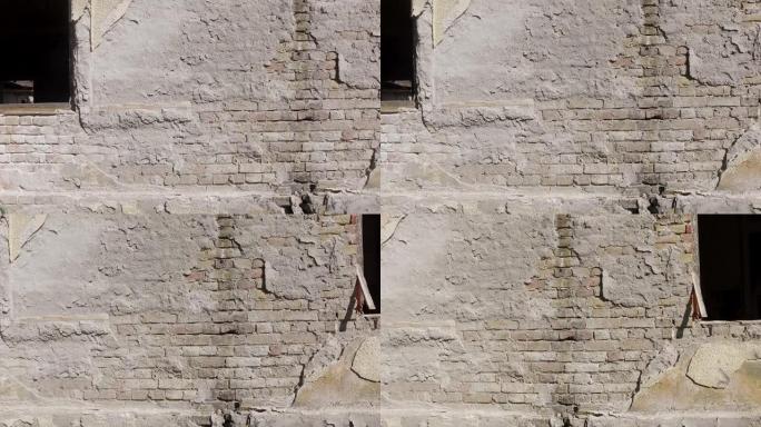 旧房屋开裂石膏外墙的不良基础，在剥皮的水泥下以砖为背景，带有运动