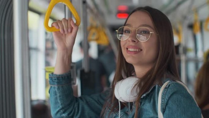年轻时尚的女人喜欢在现代电车上旅行，站在公共交通工具上喝咖啡。
