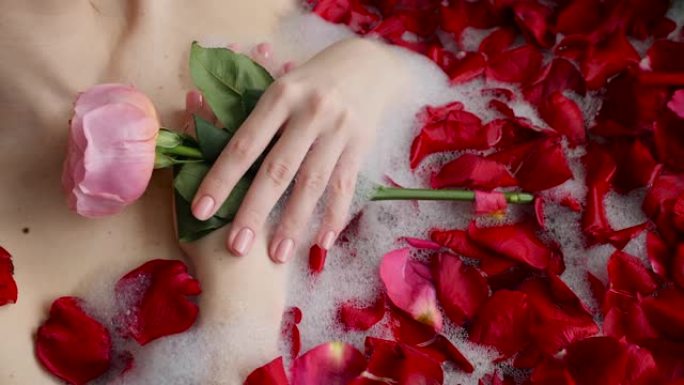 性感女孩躺在一个大石头浴缸里，手里拿着一朵玫瑰花