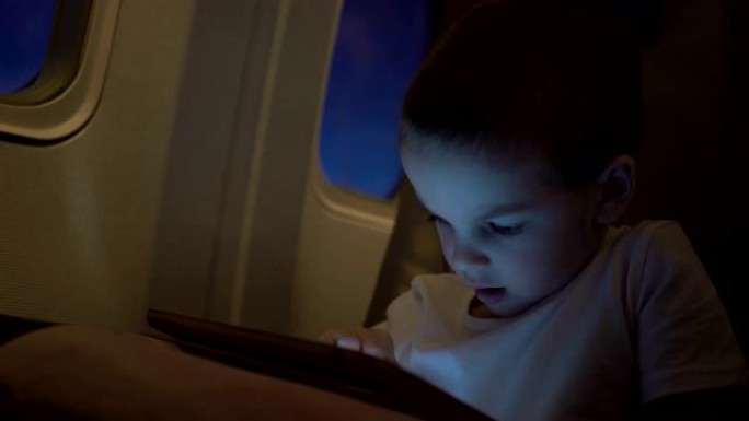 可爱的男孩坐飞机旅行，玩电脑平板电脑。超高清视频