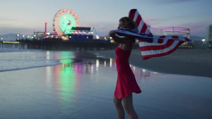 晚上在圣莫尼卡海滩上散步，同时举着美国国旗