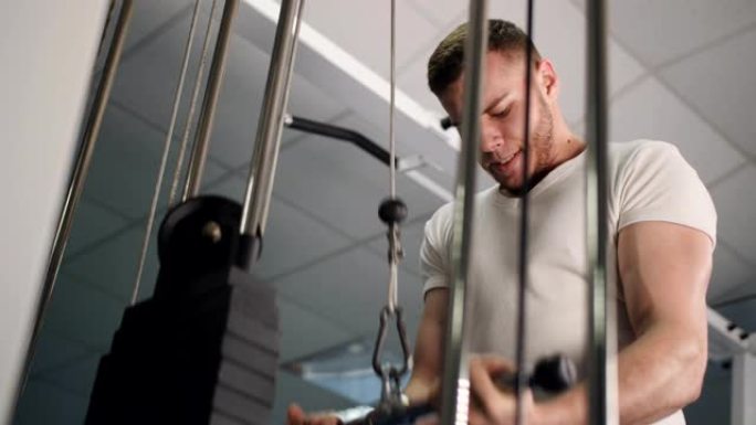男性训练手臂肱三头肌肌肉使用电缆机进行体重。男子在健身房做举重运动4k视频。锻炼健美运动概念