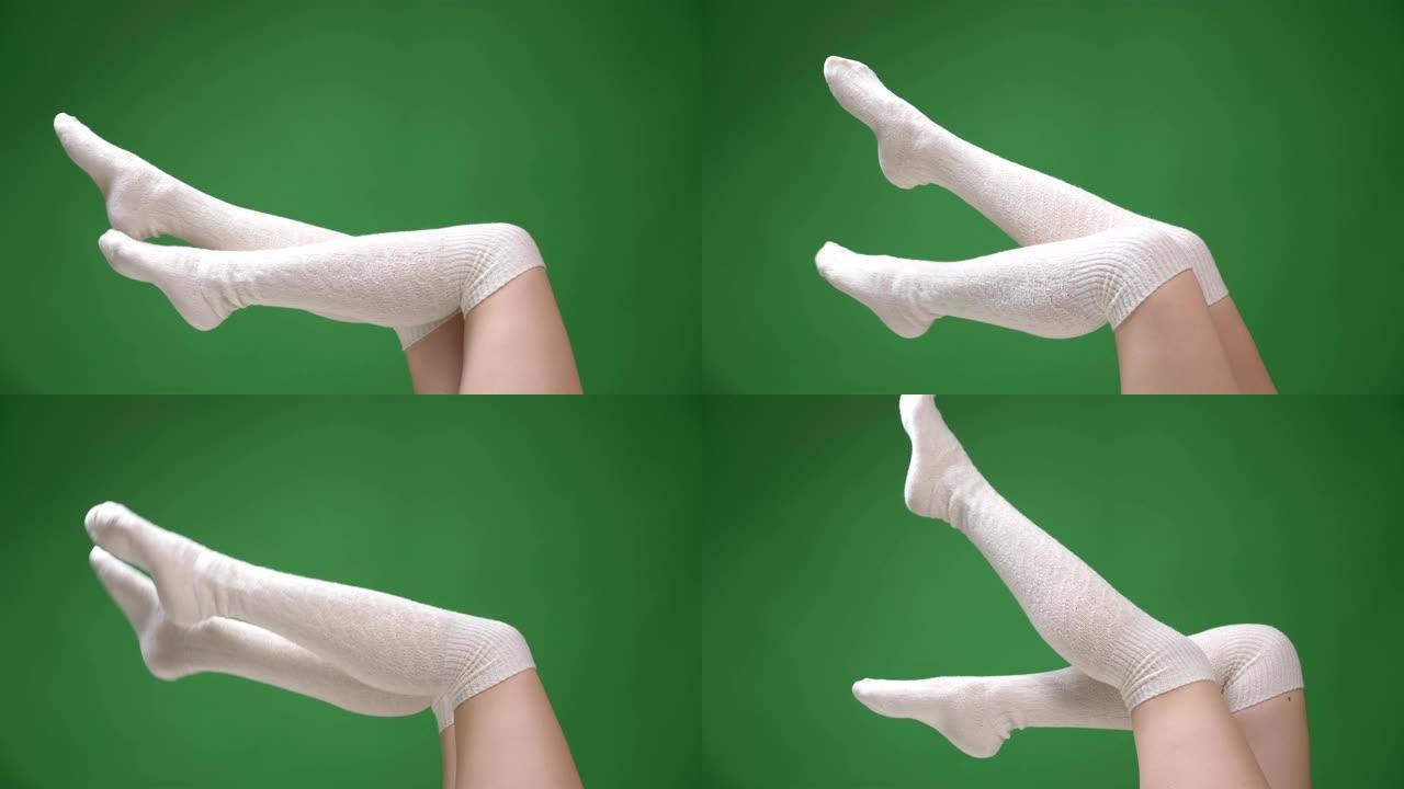 穿着可爱的白色袜子的女性青少年腿特写镜头，背景孤立在绿色上嬉戏地移动