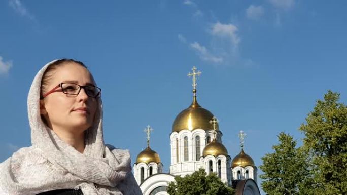戴着围巾的东正教生活方式女人站在东正教教堂的背景下