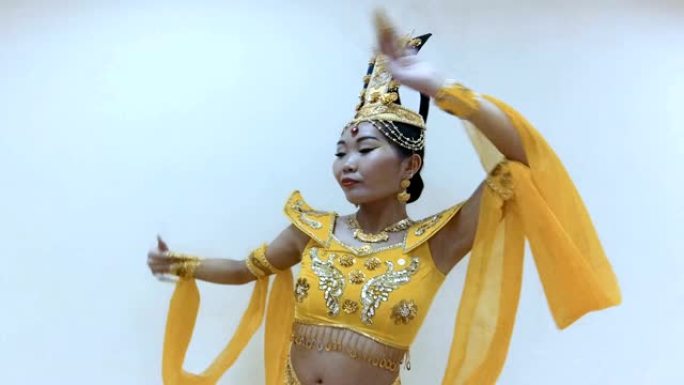 美丽的亚洲女人穿着传统的泰国黄色连衣裙，用手与长指甲修指甲跳舞