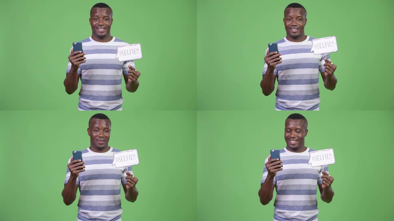 快乐的非洲年轻人拿着手机和自拍纸标志