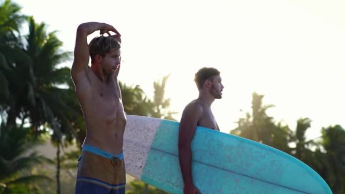 男性年轻冲浪者在一起冲浪前伸展身体。暑假的朋友。慢动作。
