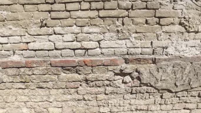 旧房屋开裂石膏外墙的不良基础，在剥皮的水泥下以砖为背景，带有运动