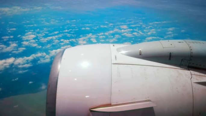 飞机飞行。飞机的机翼在云层上飞来飞去，天空多云。从飞机的窗户看。