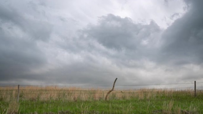 草原上的乌云笼罩着带刺的铁丝网牛栏