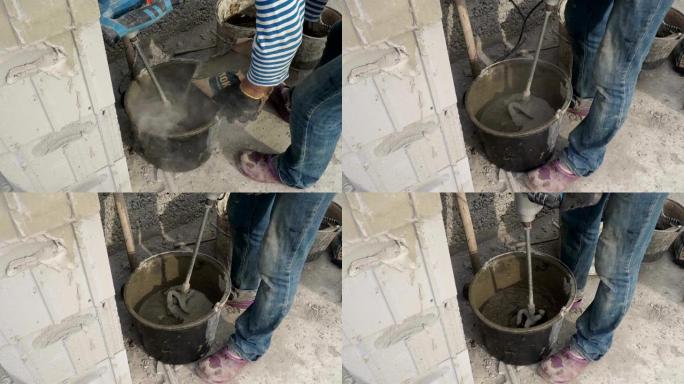 工人用搅拌机在桶中搅拌水泥砂浆