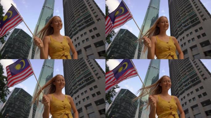 一名年轻女子挥舞着马来西亚国旗的慢镜头，背景是摩天大楼。去马来西亚旅游的概念
