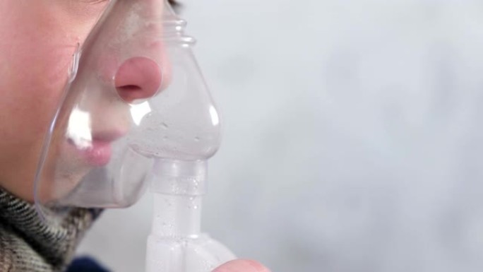 生病的男孩通过吸入器面罩吸入，鼻子和嘴唇特写侧视图。