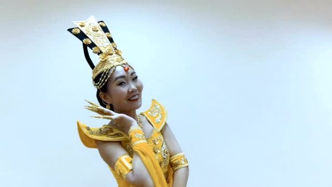 美丽的亚洲女子穿着中国传统的黄色连衣裙跳舞