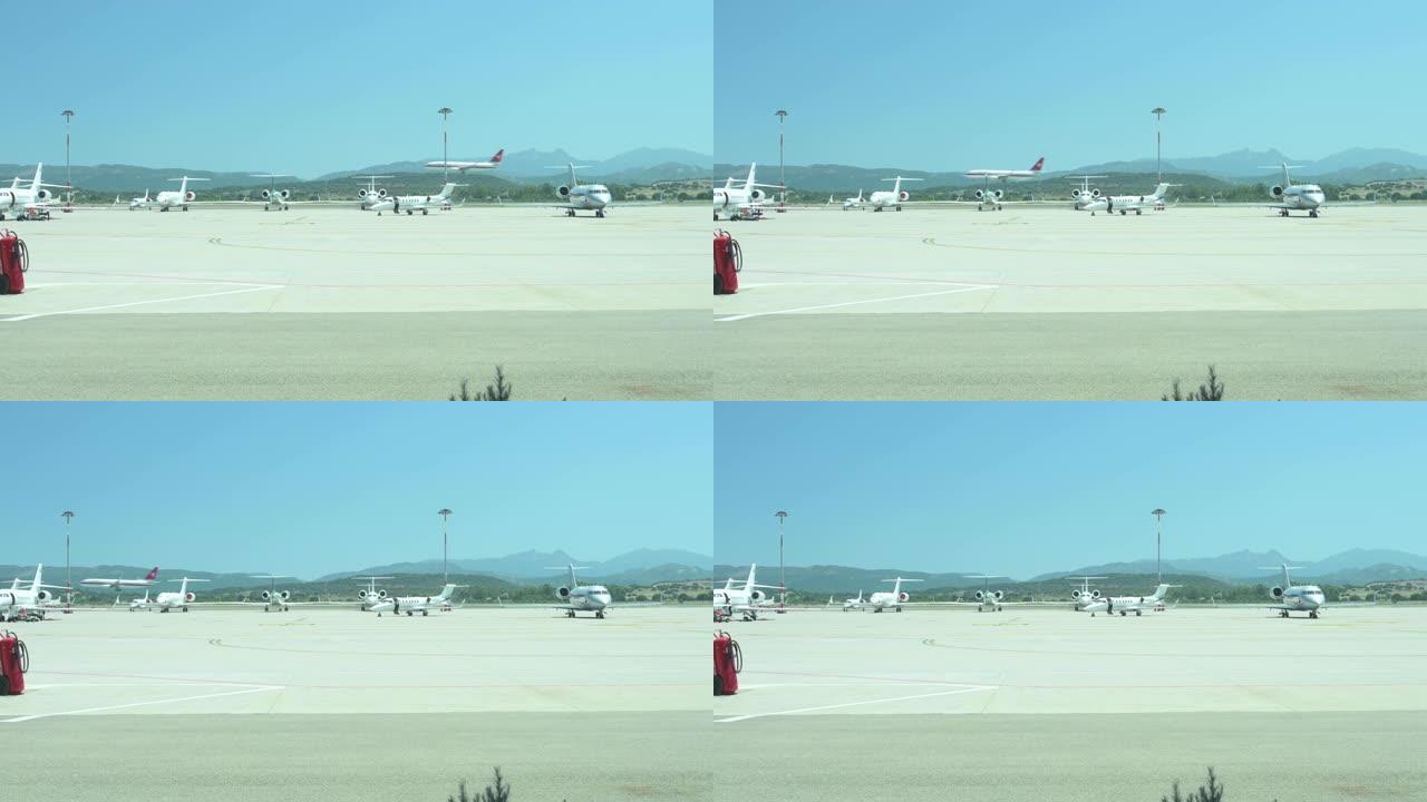 当一架商用飞机降落时，一些私人飞机停在撒丁岛机场的停车场上，令人惊叹。意大利撒丁岛。