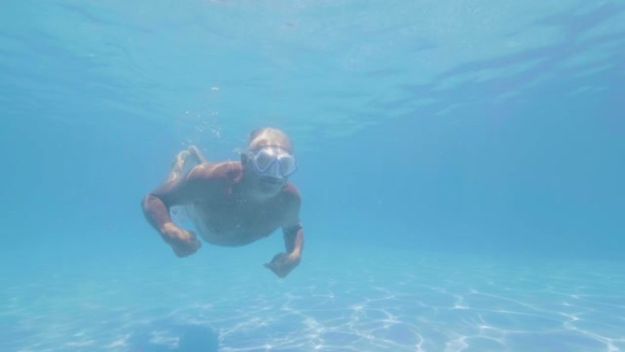 水线景观成熟男子在度假酒店游泳水下浮动游泳池。热带酒店暑假时，成年男子游泳运动员漂浮在水下游泳池。