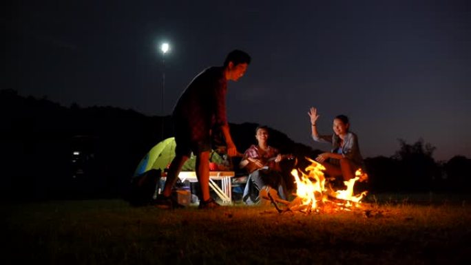 一群青少年的场景慢动作亚洲背包客在暑假期间在湖边享受篝火和野餐。他们很开心，在假期放松的时刻也很开心