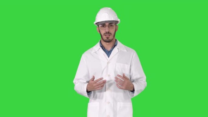 阿拉伯工程师在绿色屏幕上行走时向相机展示了一些东西，色度键