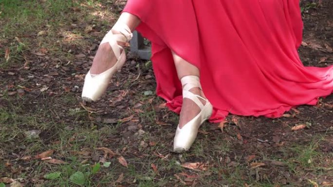 芭蕾舞女演员坐在外面绑足尖鞋