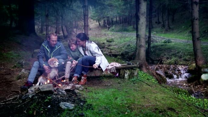 一家人坐在篝火旁烧烤棉花糖