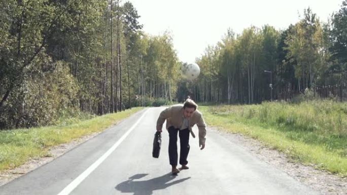 一位穿着西装，带着公文包的老年商人沿着公园旁边的马路走，用头敲打足球并与他一起玩。慢动作