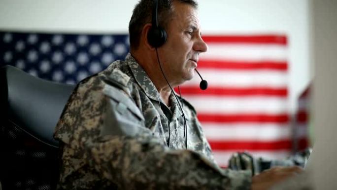 一名身穿美军制服的高级男子戴着耳机和麦克风讲话