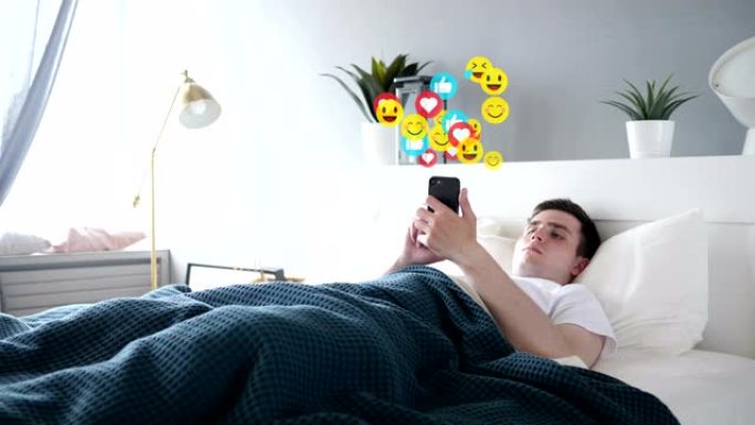 躺在床上的年轻人在智能手机，表情符号和喜欢上观看直播
