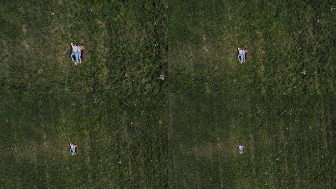 幸福的年轻夫妇躺在草地上。摄像机慢慢飞离他们。空中自上而下。4K