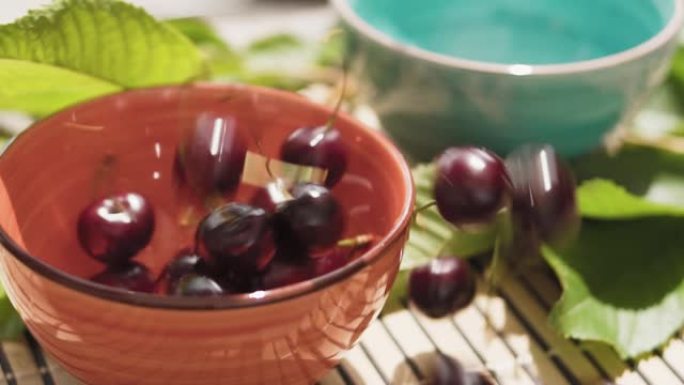 甜樱桃落在陶瓷碗里，慢动作。樱桃特写。新鲜的夏季浆果。健康食品概念。