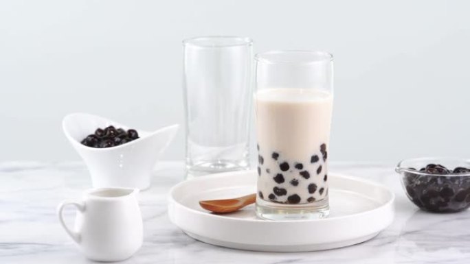 美味的木薯珍珠玻璃奶茶，明亮的大理石桌子和白色托盘上的台湾流行饮料，自制概念。4k放大拍摄视频